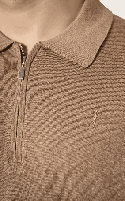Close-up of a silk polo shirt with a small logo on a neutral background